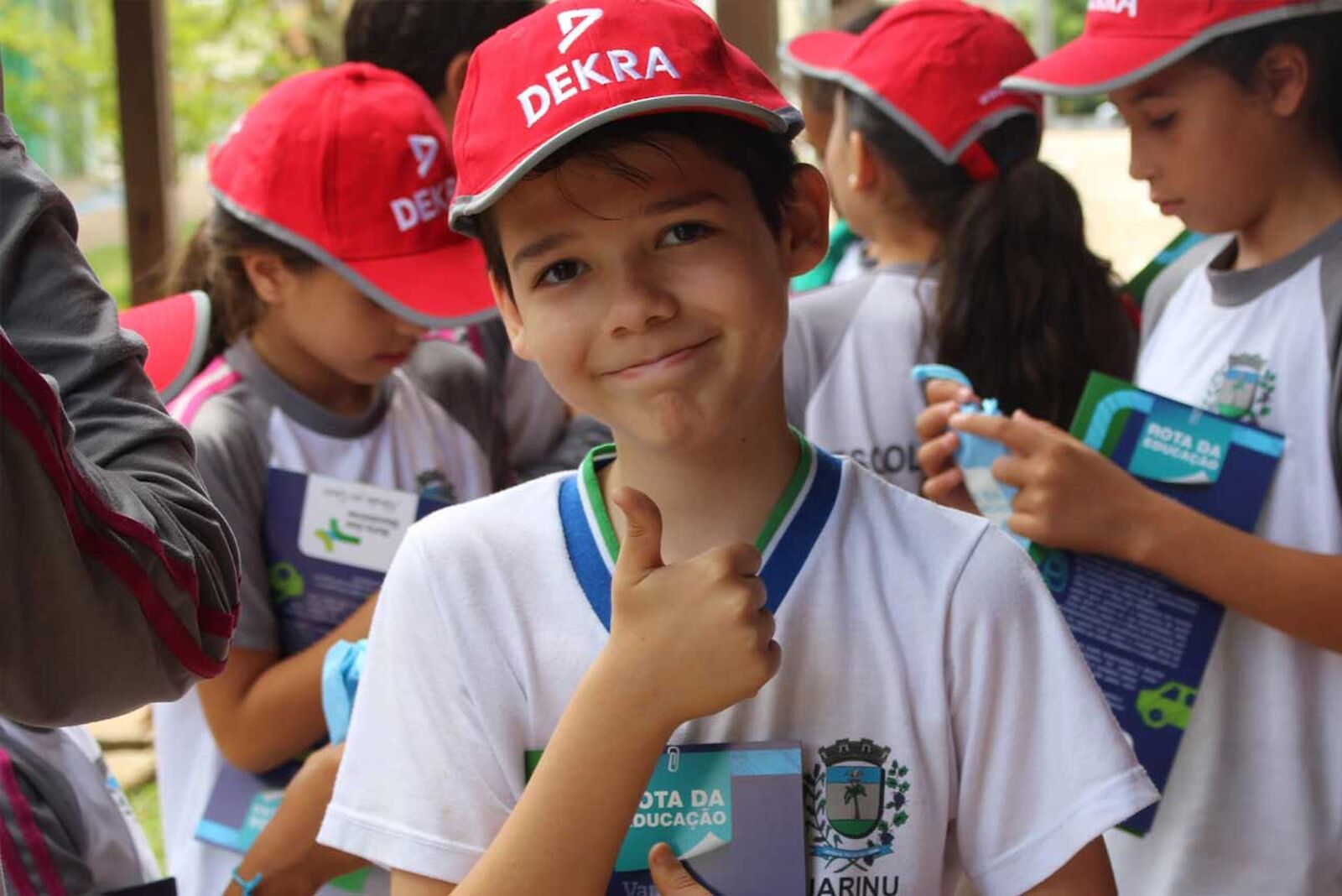 Several children with DEKRA children's caps. A boy gives the thumbs-up sign.