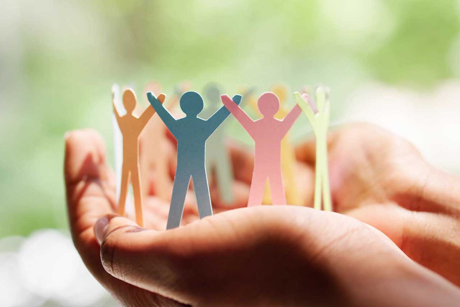 Two hands hold a wreath of colorful paper figures.